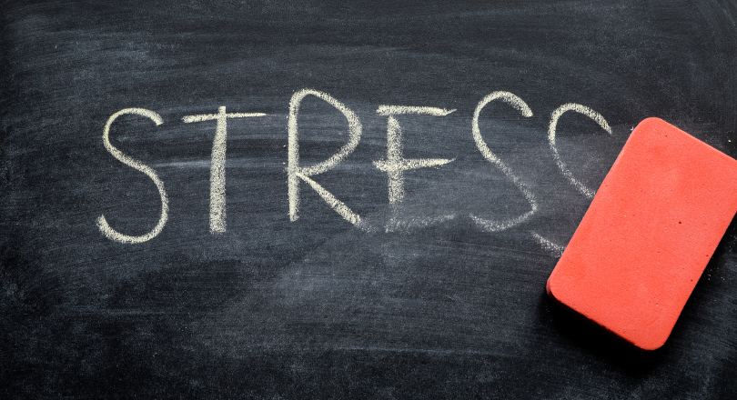An eraser rubs out the word stress on a blackboard